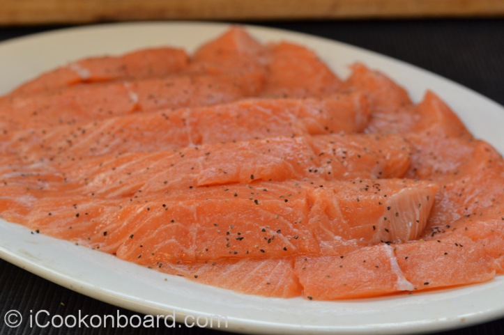 Season sliced salmon fillet with fine salt and freshly grounded black pepper.